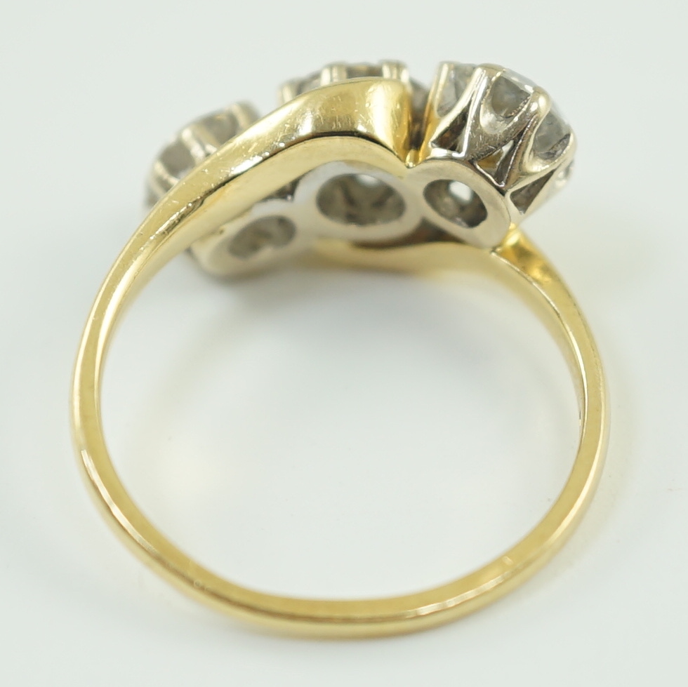 A modern 18ct gold and three stone diamond set crossover ring